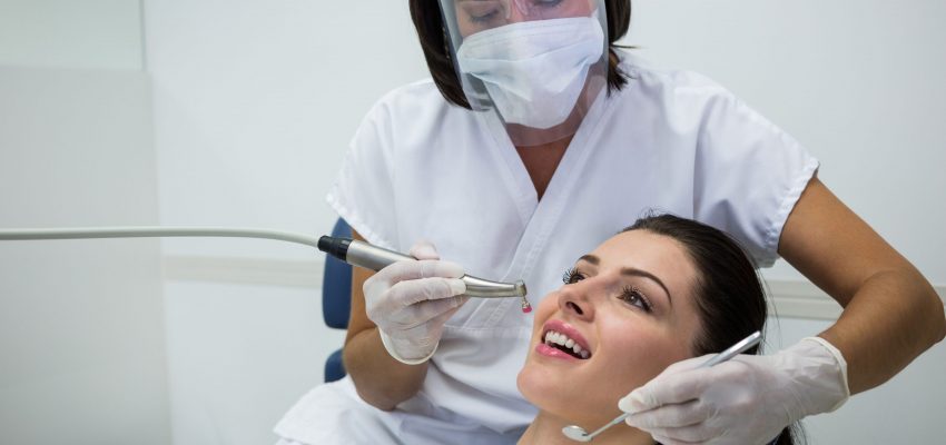 Dentist examining a female patient with tools at dental clinic