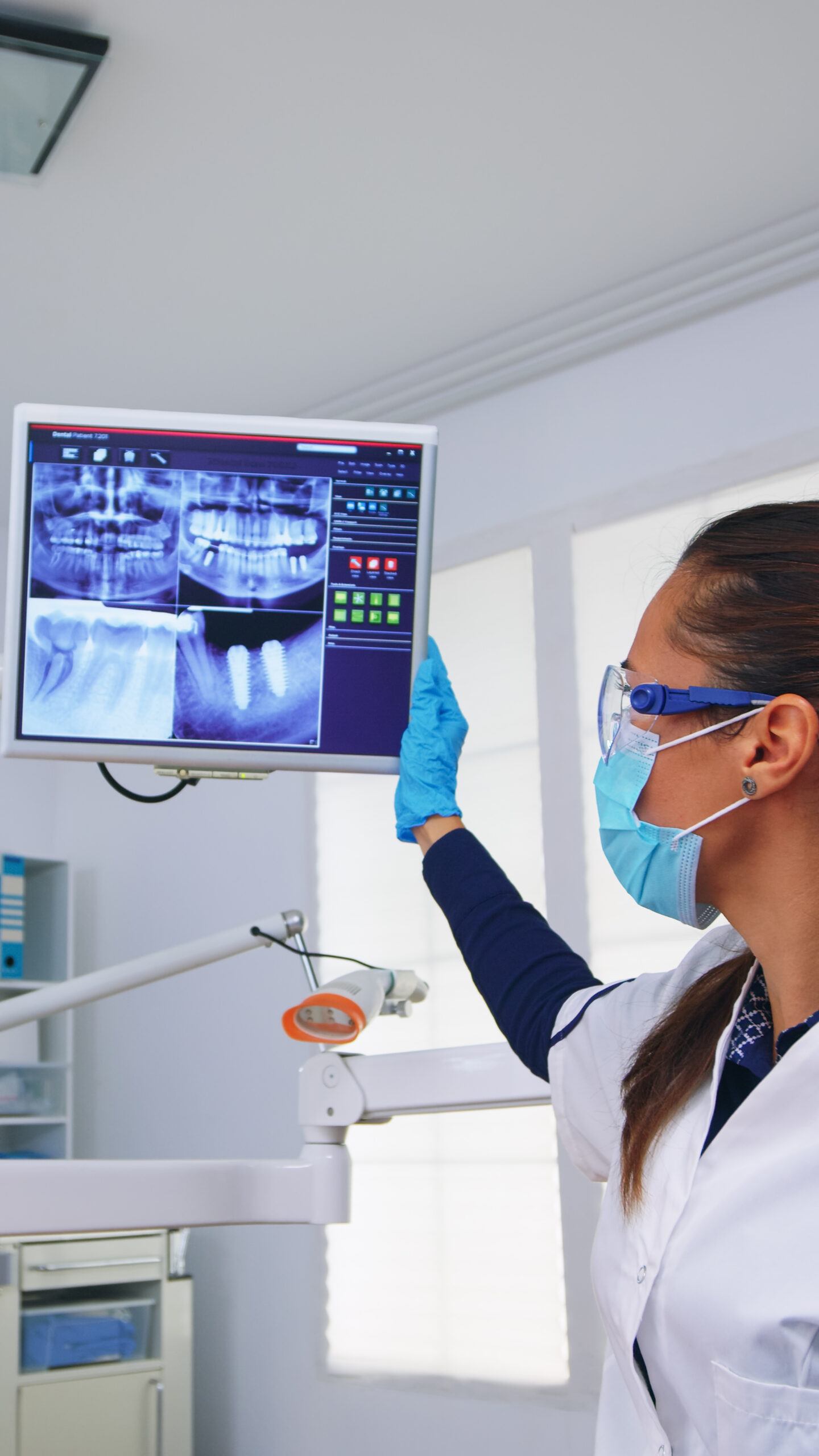 Dentist doctor and patient looking at digital teeh x-ray in dental office, person pov. Stomatology wearing protective face mask and gloves pointing at teeth radiography in stomatological clinic